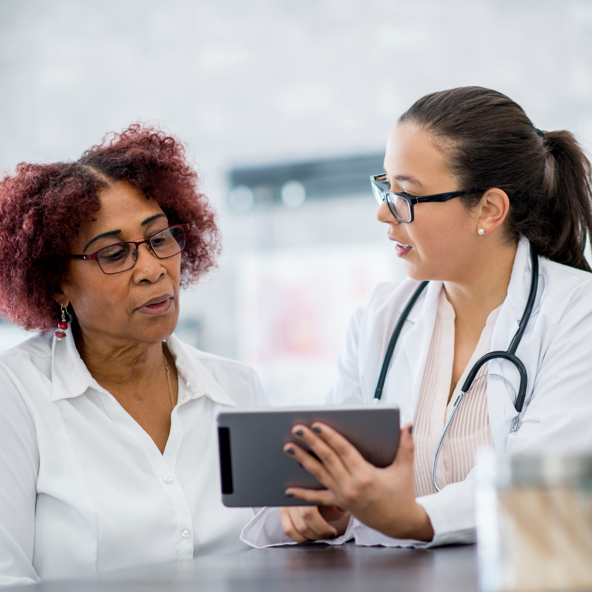 female doctors discussing notes on a tablet with female patient