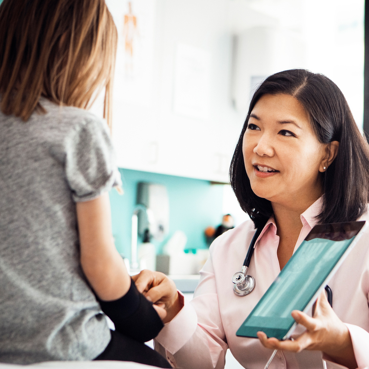 female doctor showing a young female patient notes on a tablet