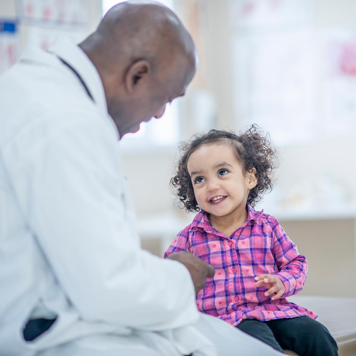 male doctor talking to smiling female child patient