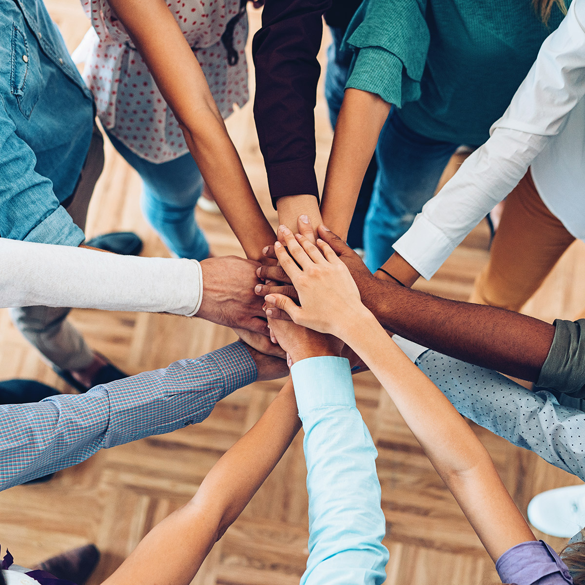 a group of people piling hands together in team spirit