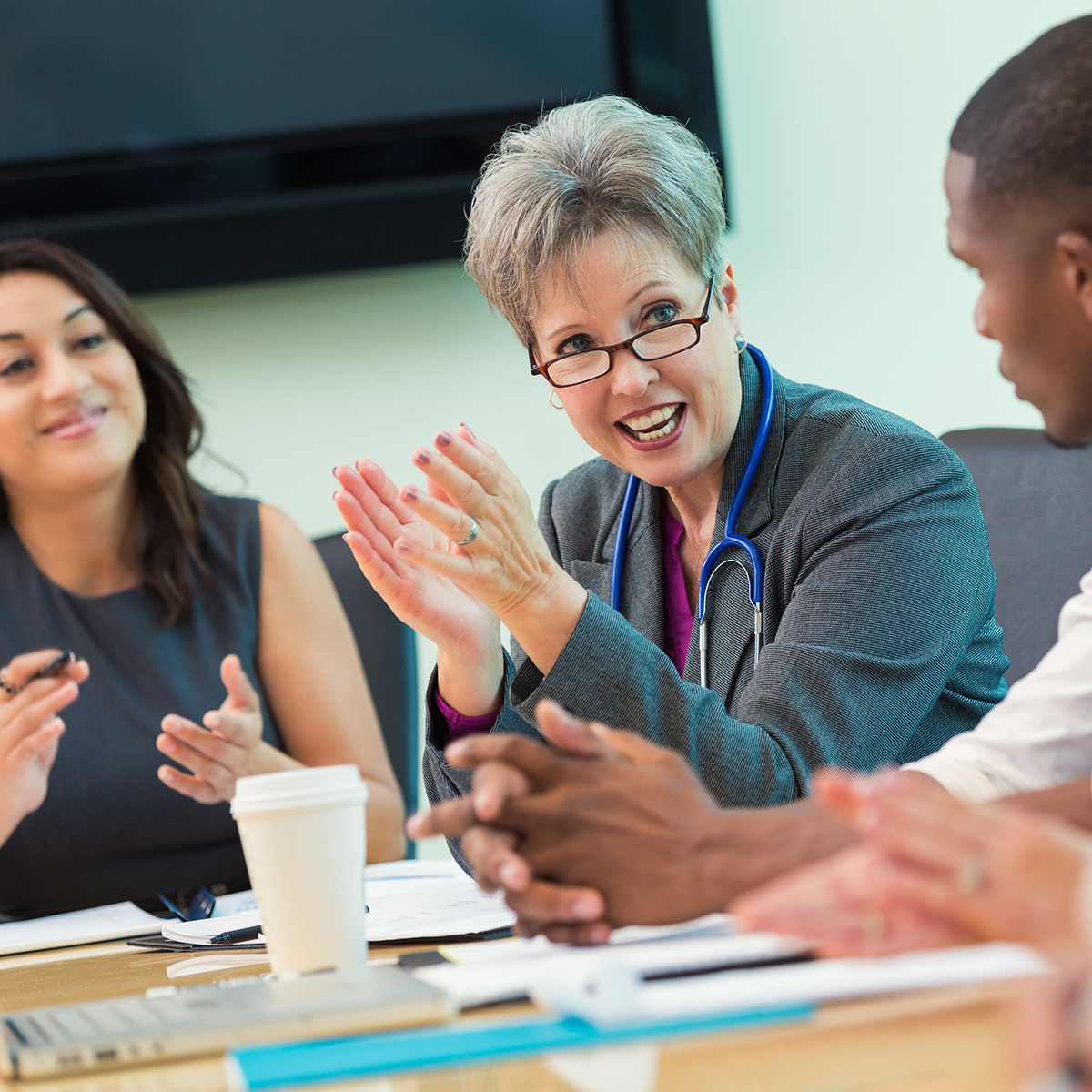 smiling executive female doctor speaking to others at a meeting