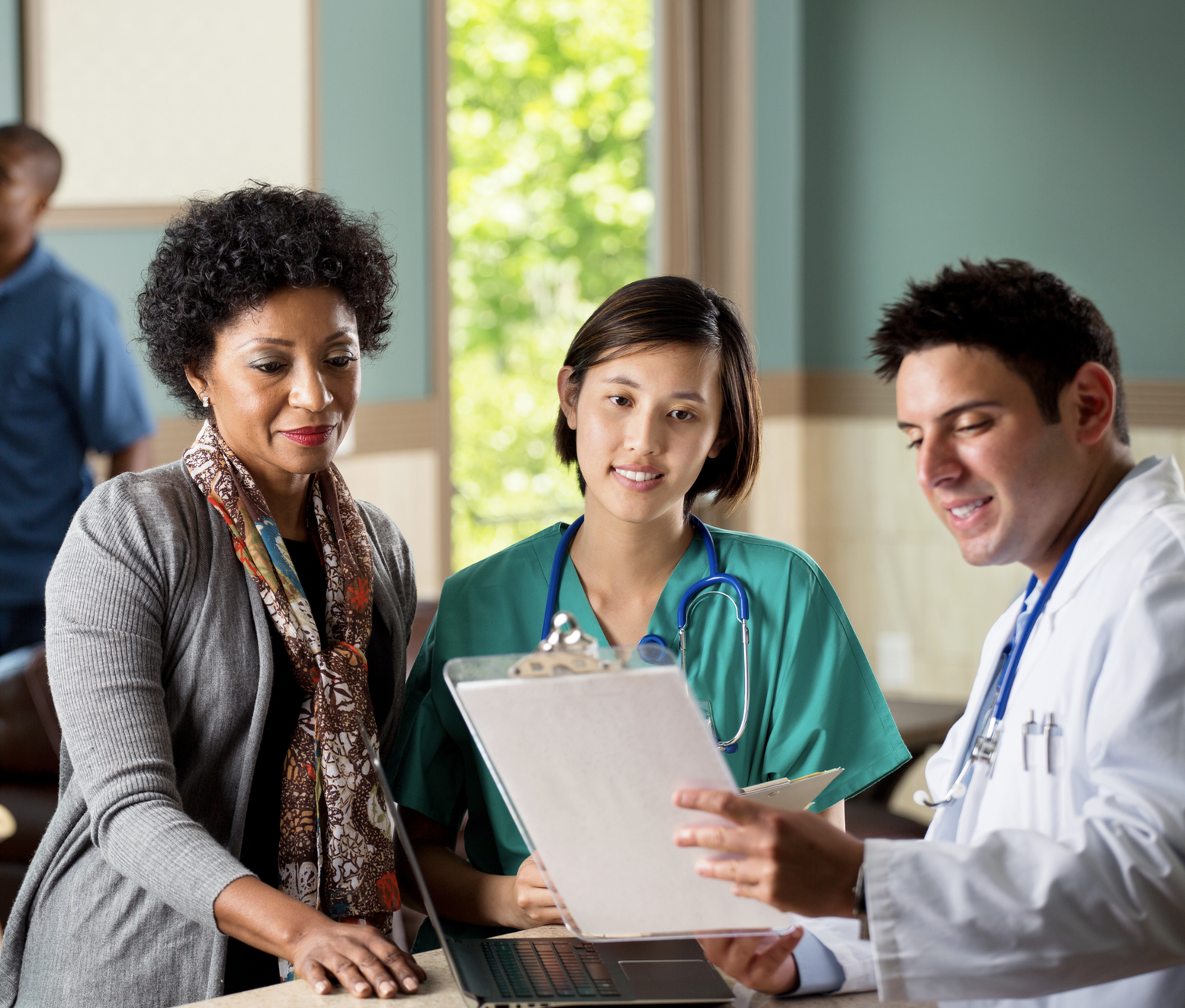 Three medical professionals examine a clipboard
